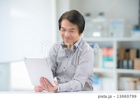室内でタブレットを操作している、カジュアルウェアー姿の中年男性 13660799