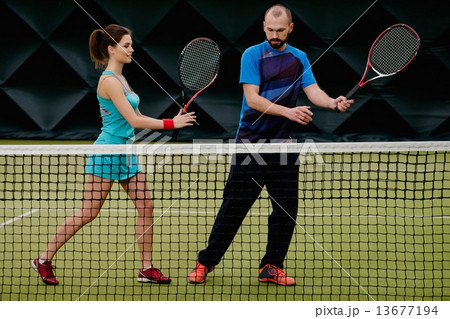 Woman player and her coach practicing on a tennis court Woman player and her coach practicing on a tennis court 13677194