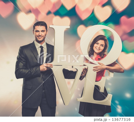 Couple holding word LOVE over blurred background Couple holding word LOVE over blurred background 13677316
