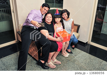Asian family taking selfie during their daughter's birthday party 13680056