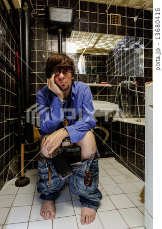 Drunk Man sits in a toilet with bottle of whiskey Drunk Man sits in a toilet with bottle of whiskey 13680416