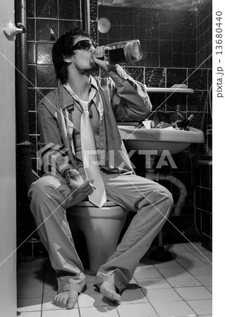 Drunk Man sits in a toile drink whiskey and smoking 13680440