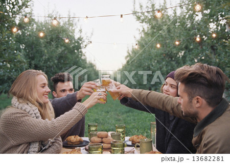 An apple orchard in Utah. Group of people toasting with a glass of cider, food and drink on a table. 13682281