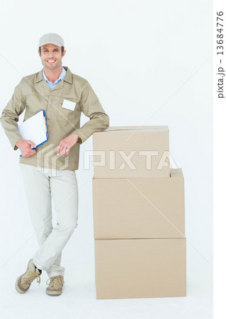 Smiling delivery man standing by stack of boxes Smiling delivery man standing by stack of boxes 13684776