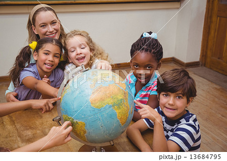 Cute pupils and teacher in classroom with globe Cute pupils and teacher in classroom with globe 13684795