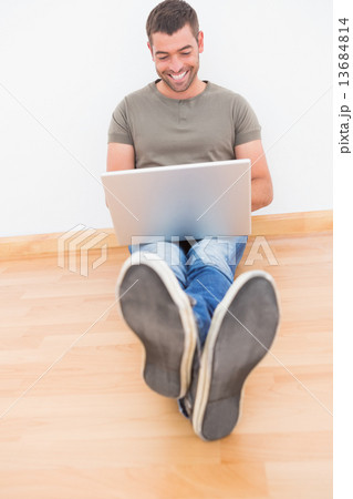 Casual man sitting on floor using laptop at home 13684814