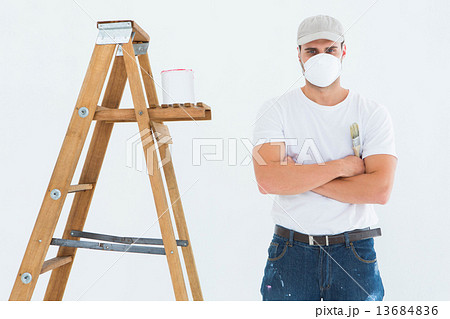 Man with paintbrush standing arms crossed by ladder 13684836