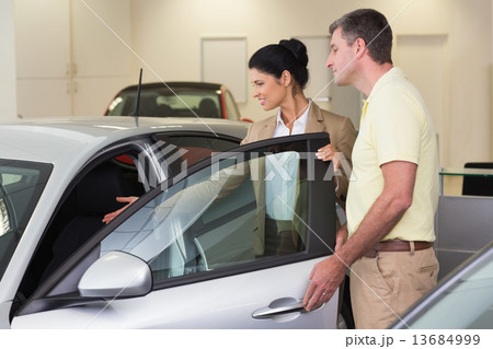 Businesswoman showing a car interior to her customers Businesswoman showing a car interior to her customers 13684999