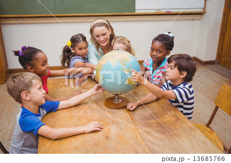 Cute pupils and teacher in classroom with globe 13685766
