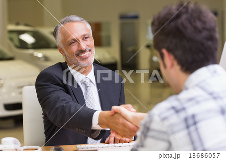 Smiling salesman shaking a customer hand Smiling salesman shaking a customer hand 13686057