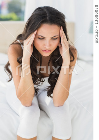 Worried brunette sitting on bed Worried brunette sitting on bed 13686058