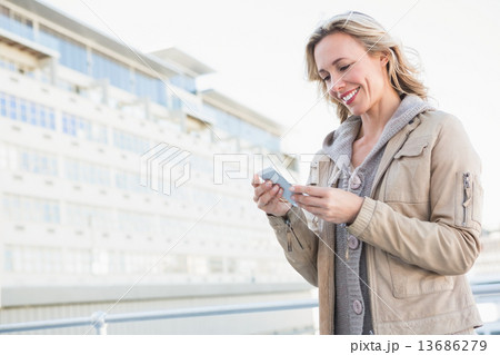 Smiling blonde standing and text messaging 13686279
