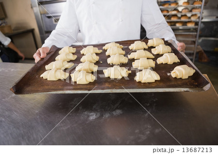 Close up of baker holding tray of raw dough 13687213