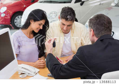 Smiling couple signing salesman contract Smiling couple signing salesman contract 13688113