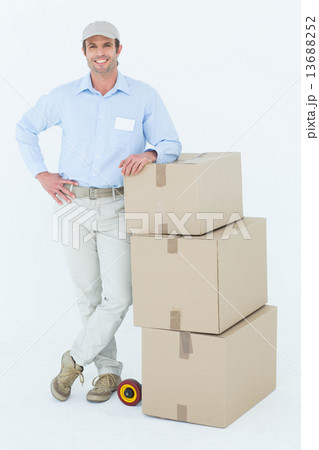 Confident delivery man leaning on stacked cardboard boxes Confident delivery man leaning on stacked cardboard boxes 13688252