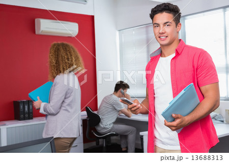 Smiling student using smartphone near classmates 13688313