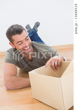 Smiling man open a moving box at home Smiling man open a moving box at home 13688529