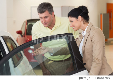Businesswoman showing a car interior to her customers 13688705
