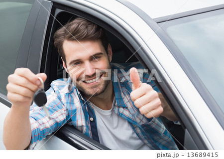 Young man smiling and holding key Young man smiling and holding key 13689415