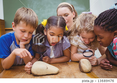 Cute pupils looking through magnifying glass Cute pupils looking through magnifying glass 13689476