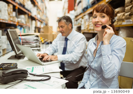 Warehouse manager working at her desk wearing headset Warehouse manager working at her desk wearing headset 13690049