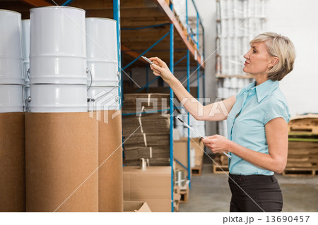 Warehouse manager checking her list on clipboard 13690457