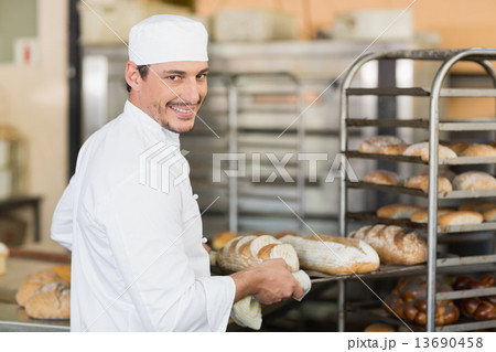 Smiling baker holding tray of bread Smiling baker holding tray of bread 13690458