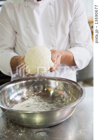 Baker forming dough in mixing bowl 13690677