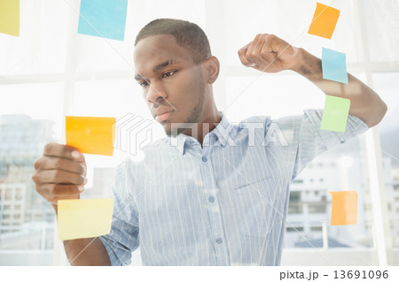 Focused businessman reading sticky notes 13691096