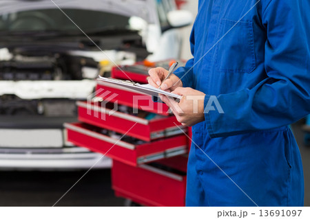 Mechanic writing on a clipboard 13691097