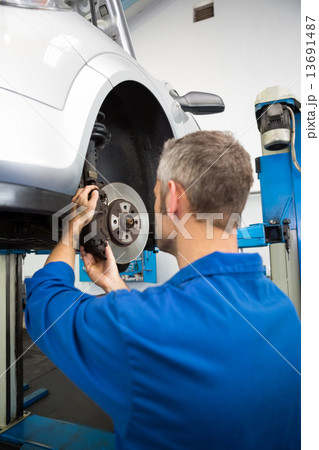 Focused mechanic adjusting the wheel 13691487