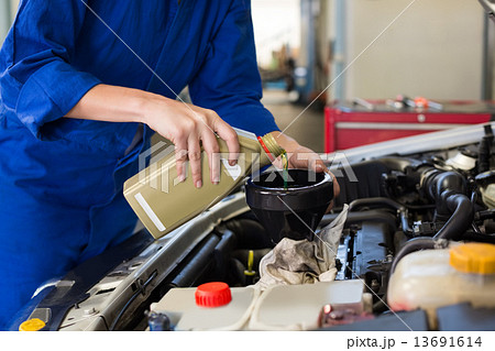 Mechanic pouring oil into car Mechanic pouring oil into car 13691614