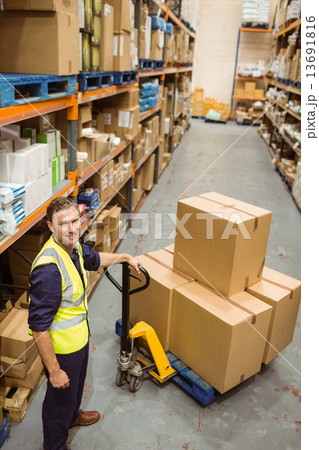 Worker with trolley of boxes smiling at camera Worker with trolley of boxes smiling at camera 13691816