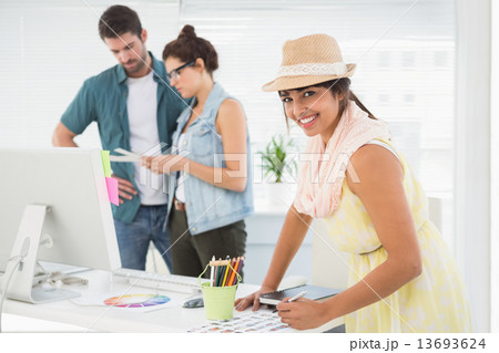 Smiling designer in front of colleagues using colour wheel Smiling designer in front of colleagues using colour wheel 13693624