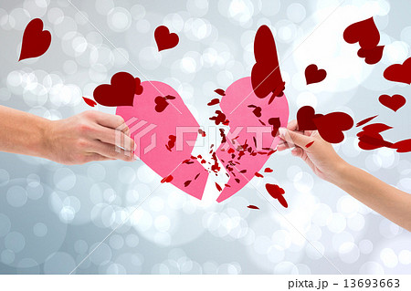 Composite image of hands holding two halves of broken heart 13693663
