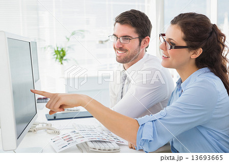 Smiling business coworkers pointing screen of computer 13693665