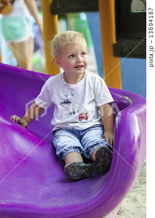 Little boy on a children's slide in the park on a walk Little boy on a children's slide in the park on a walk 13694187