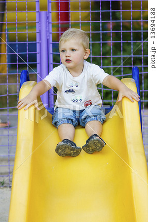 Little boy on a children's slide in the park on a walk 13694188