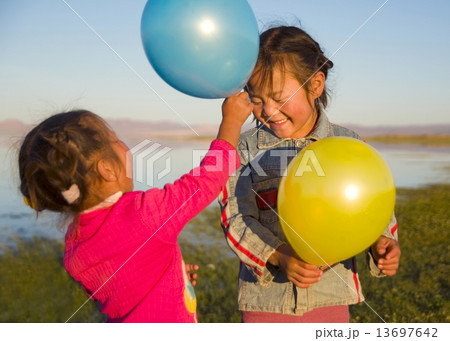 Two Little Girls Playing With Each Other With Balloons Two Little Girls Playing With Each Other With Balloons 13697642