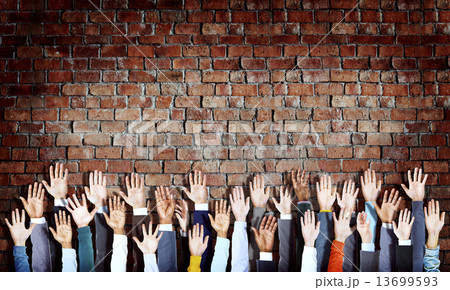 Group of Diverse Hands Raised on Brick Wall 13699593