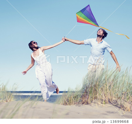 Cheerful Couple Playing Kite by the Beach 13699668