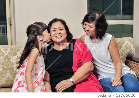 young Asian granddaughter giving a kiss to her grandmother to show her affection young Asian granddaughter giving a kiss to her grandmother to show her affection 13705020