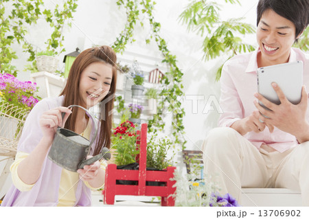 花に水遣りする女性とiPadを操作する男性 13706902