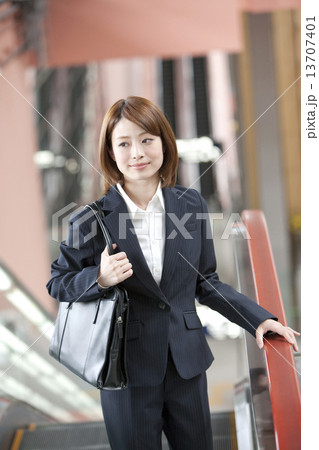 エスカレーターに乗るビジネスウーマン 13707401
