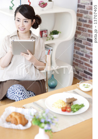 食卓でタブレットPCを見る女性 食卓でタブレットPCを見る女性 13707405