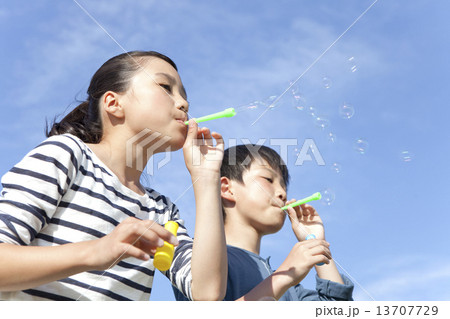 シャボン玉を吹いている子供2人の写真素材