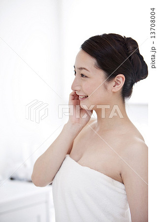 頬に手をあてる笑顔の女性の写真素材