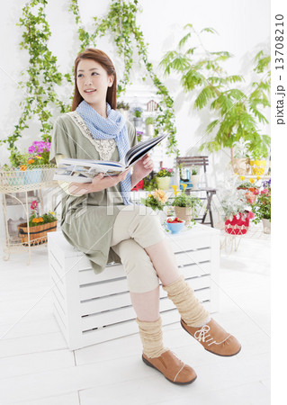 本を持って足を組んで座る女性 13708210