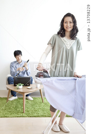 アイロン掛けをする女性とクラリネットを組み立てる男性 13708229