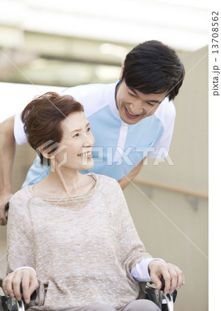 男性介護士と車いすに乗った中高年女性 13708562